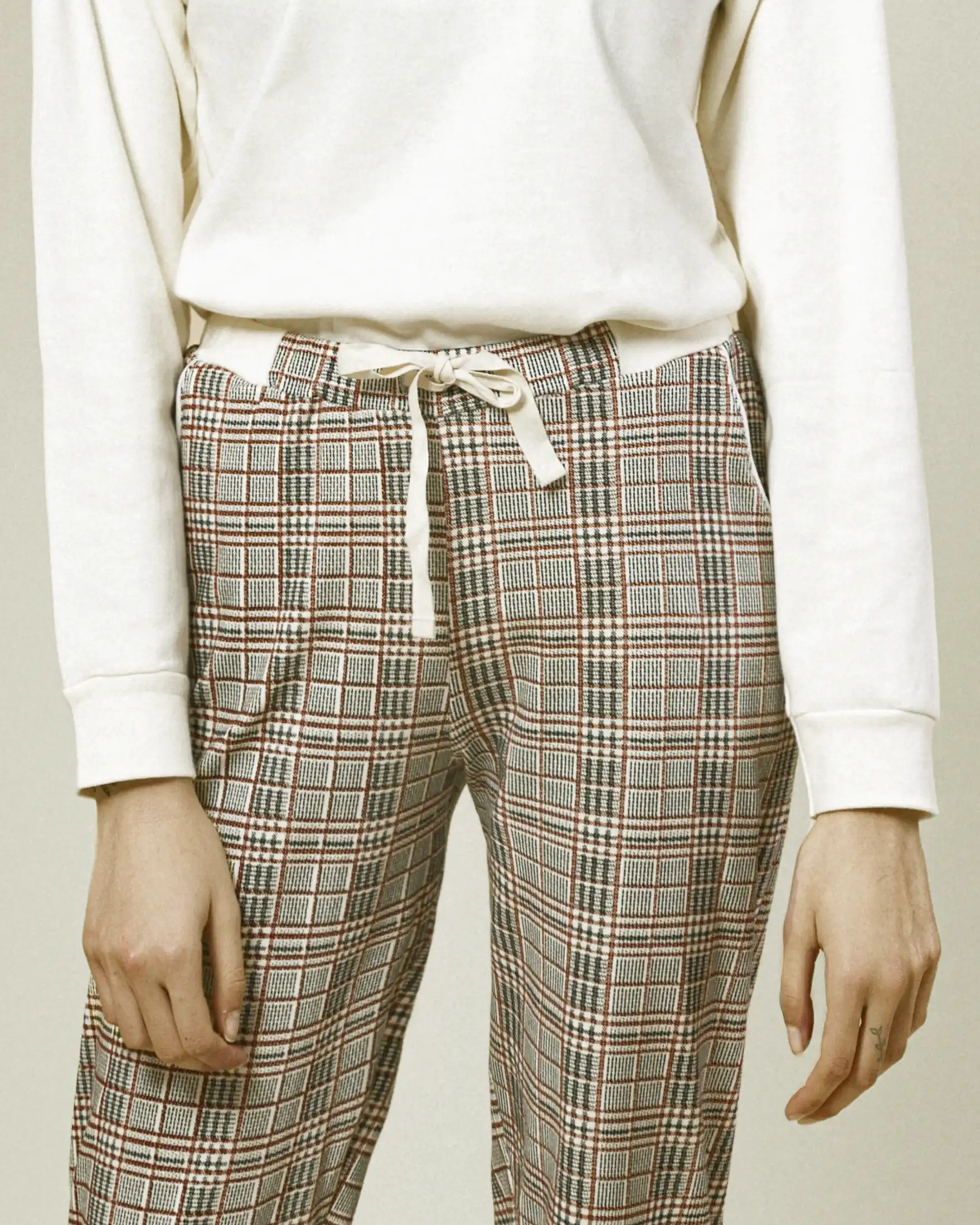 tuta donna con maglione bianco e pantaloni grigi a quadretti